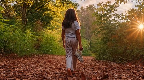 a woman walking down a path in the woods at Brvnare - Ranč Platan in Vrdnik