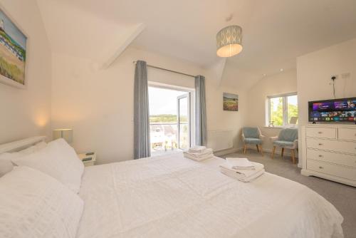 Un dormitorio con una gran cama blanca y una ventana. en Angorfa, en Y Felinheli