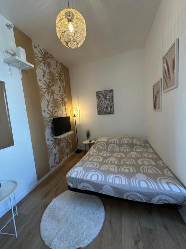 a bedroom with a bed and a table and a television at Coin cosy in Saint-Brieuc