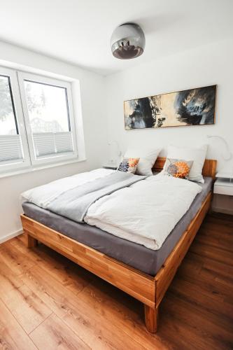 ein großes Bett in einem Zimmer mit zwei Fenstern in der Unterkunft Apartment Morgentau, mit Aussicht in Wieda & großzügigen Garten in Walkenried