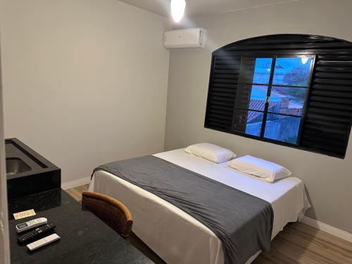 a small bedroom with a bed and a window at Hospedaria Central in Hortolândia