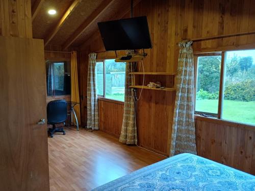 a bedroom with a bed and a television in a room at Casa de Campo in Ancud