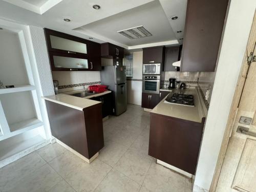 a large kitchen with brown cabinets and appliances at Comodo departamento cerca de Costera Acapulco in Acapulco