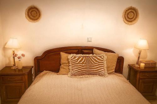 Néa PalátiaにあるOropos Cozy Houseのベッド、ナイトスタンド2台、ランプ2個を備えた寝室