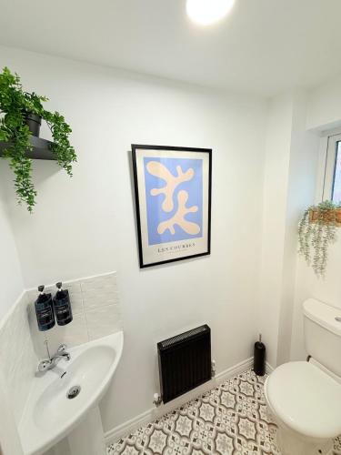 a white bathroom with a sink and a toilet at Stylish Townhouse in Rugby, sleeps up to 9! in Rugby