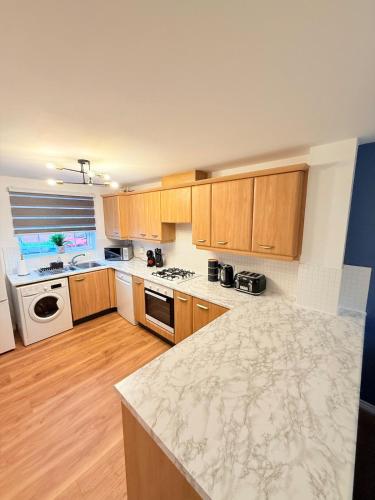 a kitchen with wooden cabinets and a marble counter top at Stylish Townhouse in Rugby, sleeps up to 9! in Rugby