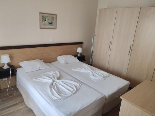 a bedroom with a bed with white sheets and pillows at Апартамент E003 в Обзор Бийч Резорт - усещането да живееш на плажа!! in Obzor
