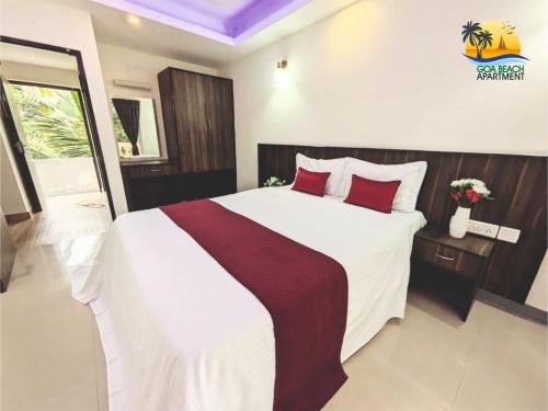 a bedroom with a large white bed with red pillows at Goa Beach Apartment in Colva
