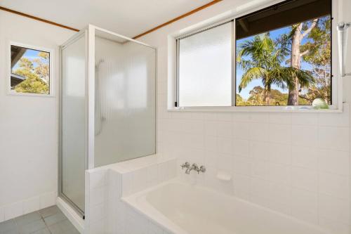 a white bathroom with a tub and a window at Peaceful and Tranquil ~ Koala Beach in Pottsville