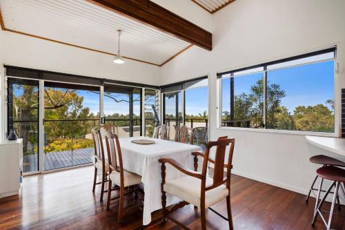 a dining room with a table and chairs and large windows at Ocean View Koala Beach Retreat in Pottsville