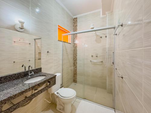 a bathroom with a toilet and a glass shower at Hotel Santiago in Lindóia