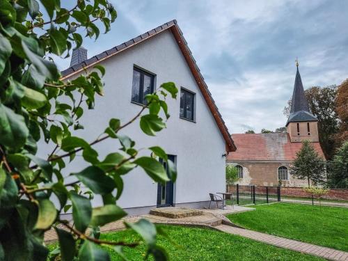 una casa bianca con una chiesa sullo sfondo di Ferienwohnung zur Schlossruine a Boldekow