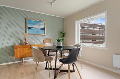 a dining room with a table and chairs and a window at Cozy and spacious apartment in city centre in Tromsø