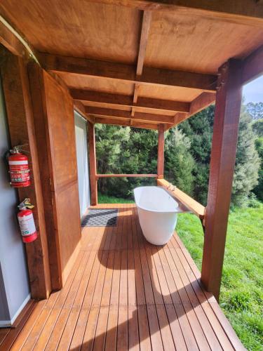 a large wooden deck with a bath tub on it at Glenwood Akaroa Bush Retreat - Kanuka Hut in Akaroa