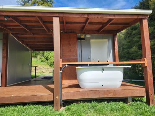 a bath tub on a deck with a house at Glenwood Akaroa Bush Retreat - Kanuka Hut in Akaroa