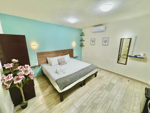 a bedroom with a bed and a vase with flowers at Habitaciones Bacalar MYD in Bacalar