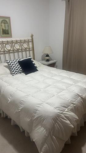 a white bed with a black pillow on it at Croeso! in Puerto Madryn