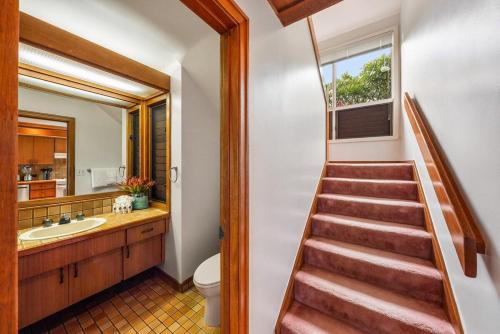 a staircase leading to a bathroom with a sink and a toilet at Kapalua Ridge Villas 1011 · KRV 1011 Oceanview Condo + Golf + Lu in Kahana