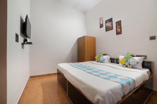 um quarto com uma cama e uma TV na parede em Hotel O Home Gautam Homestay em Dehradun