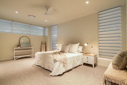 a bedroom with a white bed and a window at Lighthouse Peek - Luxury, Central, Private Pool in Byron Bay