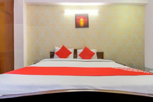 a bedroom with a large bed with red pillows at Hotel O Kamini in Patna