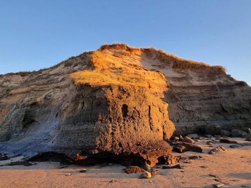 a large cliff on a sandy beach with a mountain at Luxury Spa Retreat in Lokken - By Traum Ferienwohnungen in Løkken
