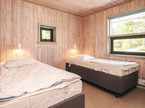 海尔斯4 person holiday home in Hals的配有木墙和窗户的客房内的两张床