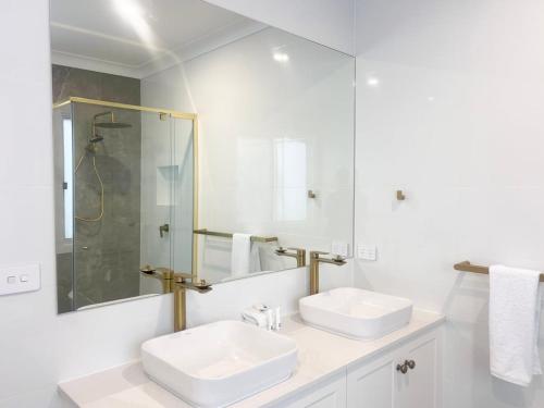 a white bathroom with two sinks and a shower at Eliza's Escape 2 Wagga CBD in Wagga Wagga