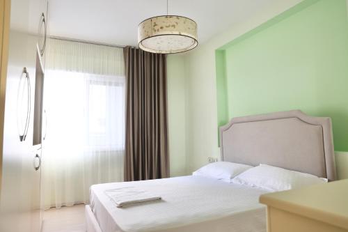 a bedroom with a white bed and a window at Casa Miel en el Botánico in Tirana