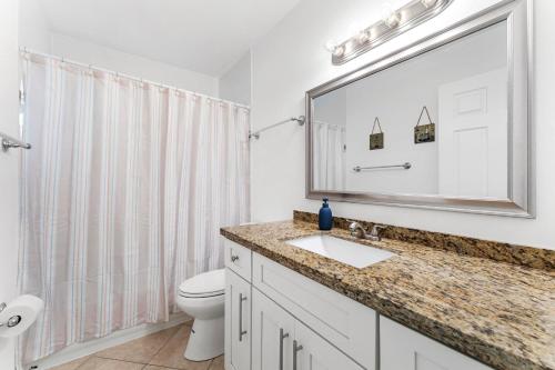 une salle de bain avec un lavabo, des toilettes et un miroir dans l'établissement Jupiter Coastal Cottage, à Jupiter