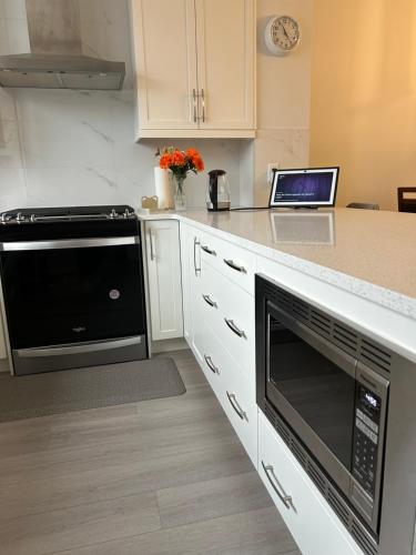 a kitchen with a stove and a microwave at Sunny Queen-size Bedroom with Private Bath in Brand New House in Calgary