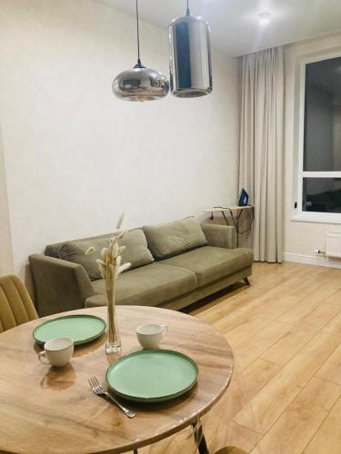 una sala de estar con una mesa y un sofá en Современные, светлые и уютные апартаменты в центре Астаны, en Astana