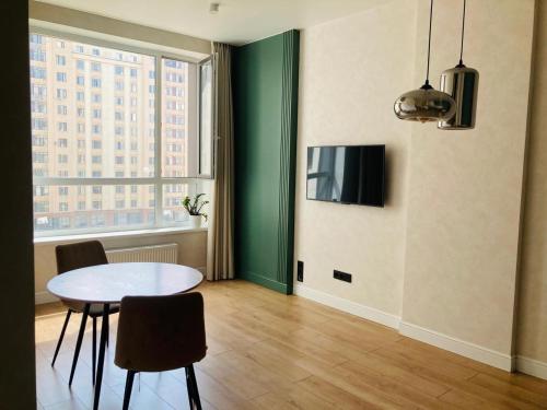 Una sala de estar con una mesa y sillas y un televisor. en Современные, светлые и уютные апартаменты в центре Астаны, en Astana