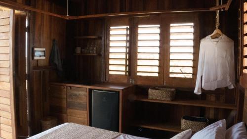 a bedroom with a bed and a window and a shelf at Mangal Amaniū in Camocim