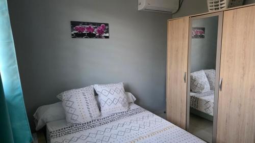 Un dormitorio con una cama con almohadas blancas y un espejo. en La fleur de lune, en Cabassou