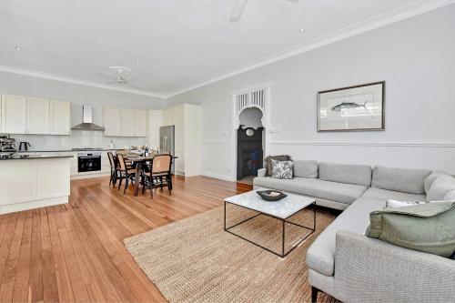 a living room with a couch and a table and a kitchen at Tosca Elegant Merewether Beach House with Pool in Merewether
