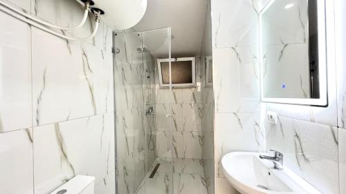 Un baño blanco con ducha y lavabo. en The Central Spot, en Tirana