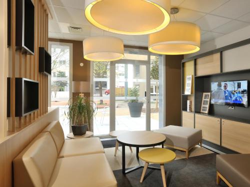 een woonkamer met een bank en een tafel bij B&B HOTEL Lyon Caluire Cité Internationale in Caluire-et-Cuire