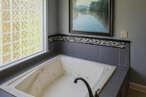 een badkuip in een badkamer met een groot raam bij Lakefront Luxury: Dock Fire Pit Game Room More in Lake Murray Shores