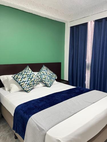 a bedroom with a bed with blue walls and pillows at Hotel Grand Galaxie in Caracas