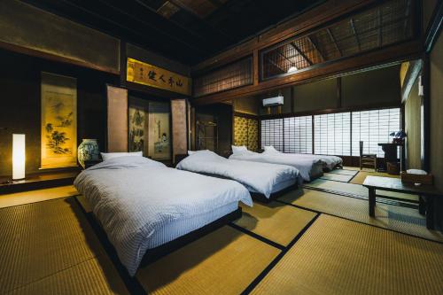1 Schlafzimmer mit 3 Betten in einem Zimmer in der Unterkunft Gateway to Hakuba & Snow Monkey - Historic 200yo Home in Nagano
