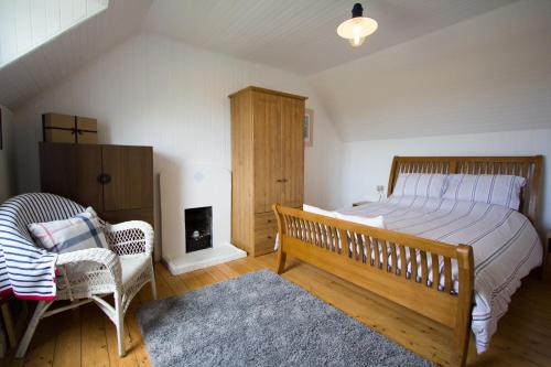 um quarto com uma cama, uma cadeira e uma lareira em Lighthouse Cottage (Shared Facilities) em Earlish