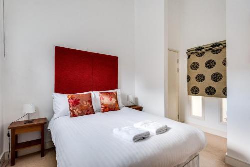 a bedroom with a white bed with a red headboard at Elegant Oxford Flat - Central Spacious Comfortable in Oxford