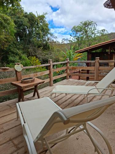 una terraza con 2 tumbonas y una mesa en Chalé Beira Rio Cipó, en Serra do Cipo