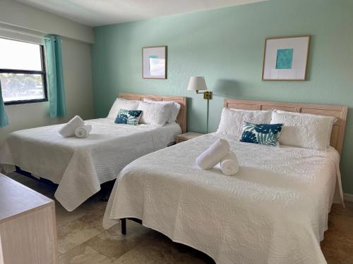 クリアウォーター・ビーチにあるBeachfront Condo, Direct Access to Sugar Sand Beach, Heated Pool and Balcony Viewsの白いシーツが敷かれたベッドが2つある寝室