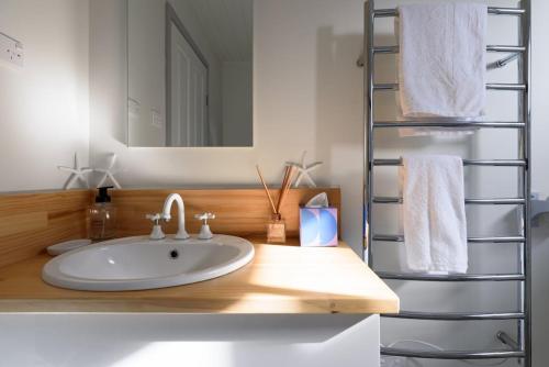 a bathroom with a sink and a shelf with towels at Lulworth Coastal Getaway - Close To The Beach in Lulworth