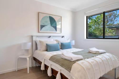 ein weißes Schlafzimmer mit einem großen Bett mit blauen Kissen in der Unterkunft Oleander Cottage in Lake Albert