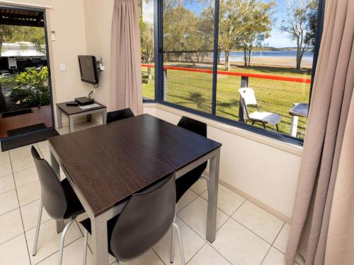 a dining room with a table and chairs and a window at Lakeside Forster Holiday Park in Forster