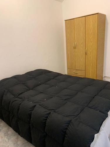 a bedroom with a large black bed and a wooden cabinet at La Morada de sus Sueños II in San Roque