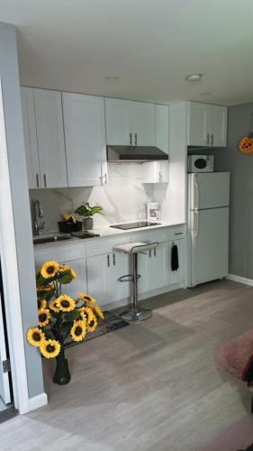 a kitchen with white cabinets and a vase of sun flowers at Unit #10 Private Studio in Hempstead
